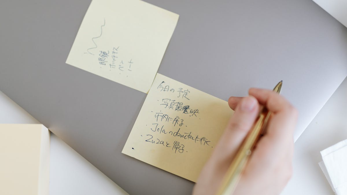 Hand schrijft op gele sticky notes — tips bij het opstellen van algemene voorwaarden